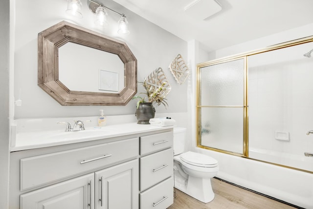 bathroom featuring bath / shower combo with glass door, vanity, toilet, and wood finished floors