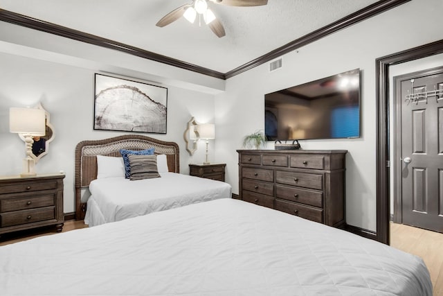 bedroom featuring wood finished floors, a ceiling fan, baseboards, visible vents, and crown molding