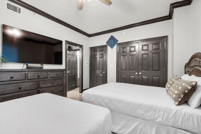 bedroom with a textured ceiling, ornamental molding, a closet, and visible vents