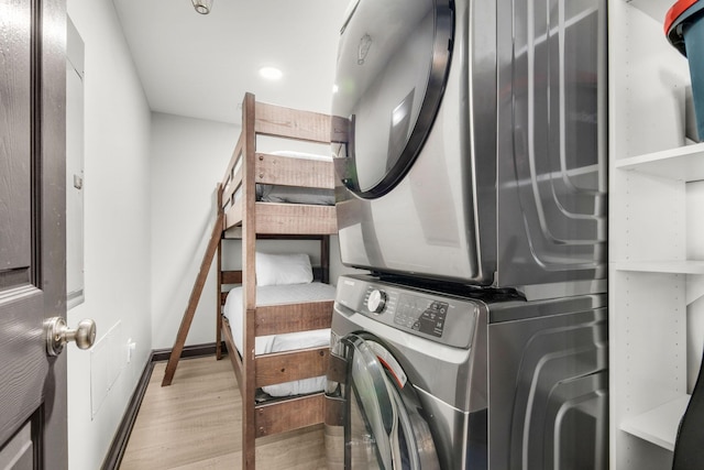 clothes washing area with laundry area, wood finished floors, and stacked washer and clothes dryer