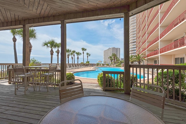 wooden deck featuring outdoor dining space and a community pool