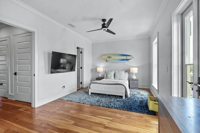 bedroom featuring ornamental molding, visible vents, ceiling fan, and wood finished floors