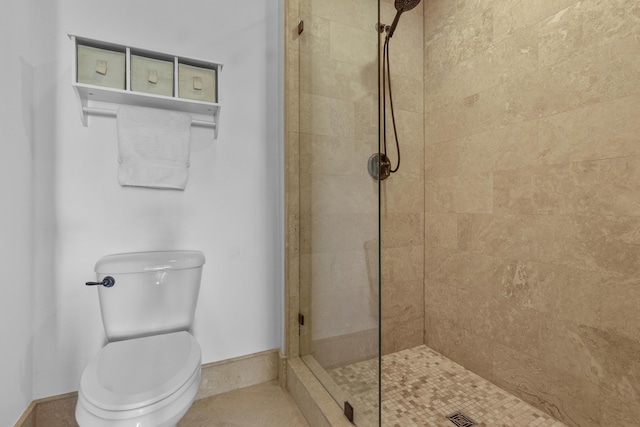 bathroom with toilet, baseboards, and a tile shower