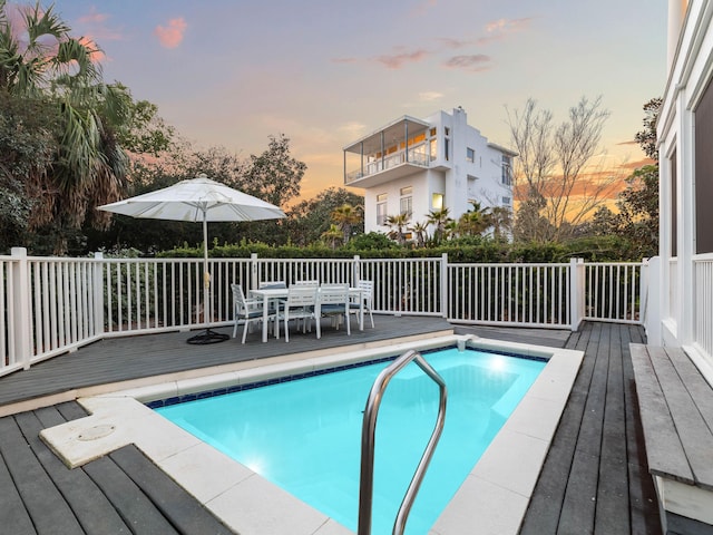 view of swimming pool with outdoor dining area, a fenced in pool, and a wooden deck