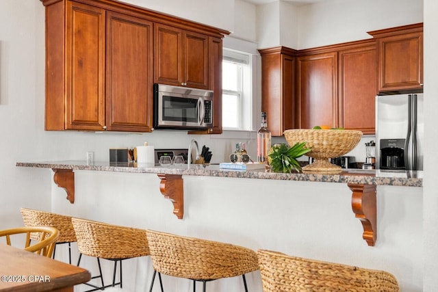 115 Cottage Ct, Panama City Beach, FL 32413 - kitchen featuring light stone countertops, appliances with stainless steel finishes, and a breakfast bar