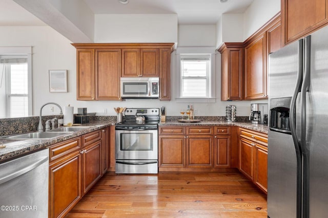 115 Cottage Ct, Panama City Beach, FL 32413 - kitchen with appliances with stainless steel finishes, sink, light wood-type flooring, and dark stone counters