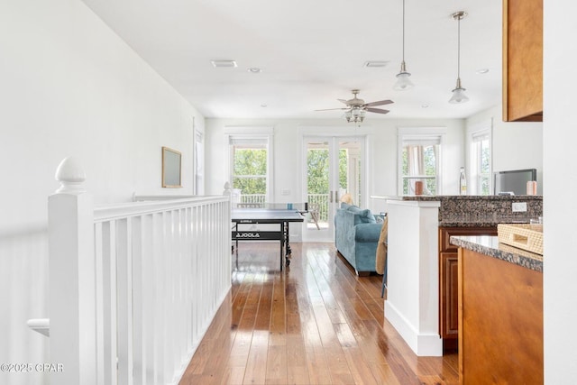 115 Cottage Ct, Panama City Beach, FL 32413 - kitchen with hanging light fixtures, dark stone counters, ceiling fan, and light wood-type flooring