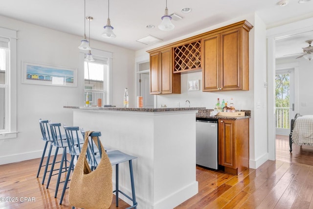 115 Cottage Ct, Panama City Beach, FL 32413 - kitchen with light hardwood / wood-style flooring, a breakfast bar, dark stone countertops, hanging light fixtures, and stainless steel dishwasher