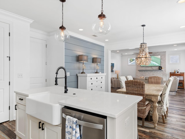 kitchen featuring light countertops, stainless steel dishwasher, an island with sink, and white cabinetry