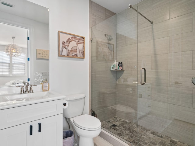 full bathroom featuring a notable chandelier, visible vents, toilet, a shower stall, and vanity