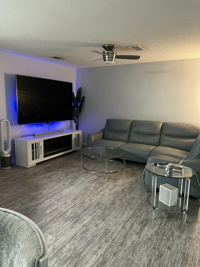 living room featuring ceiling fan, wood-type flooring, and a textured ceiling