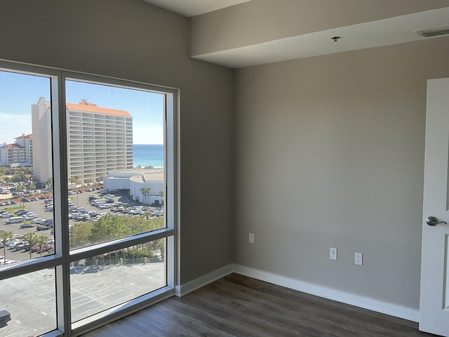 unfurnished room featuring a water view and dark hardwood / wood-style floors