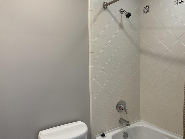 bathroom featuring toilet and tiled shower / bath