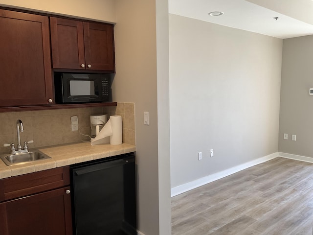 kitchen with dark brown cabinets, sink, black appliances, and backsplash