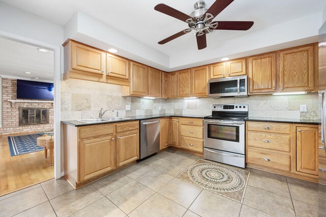 117 Hibiscus Ave, Gulf Breeze, FL 32561 - kitchen featuring a fireplace, stainless steel appliances, decorative backsplash, a sink, and dark stone counters
