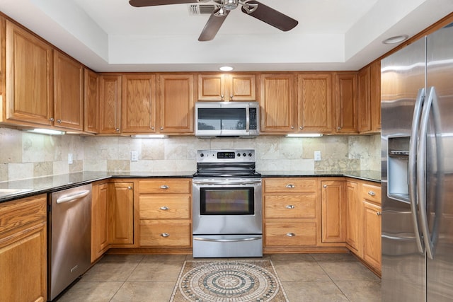 117 Hibiscus Ave, Gulf Breeze, FL 32561 - kitchen featuring a raised ceiling, stainless steel appliances, brown cabinetry, and backsplash