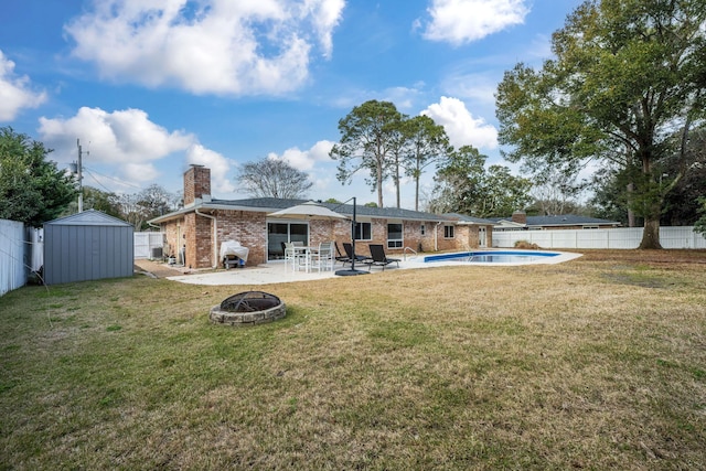 117 Hibiscus Ave, Gulf Breeze, FL 32561 - back of house with a fenced backyard, a fire pit, an outdoor structure, a fenced in pool, and a storage unit