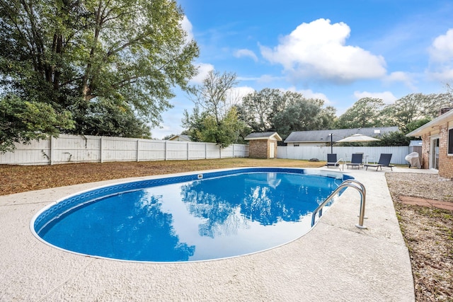 view of swimming pool with a fenced in pool, a patio, a fenced backyard, a storage unit, and an outdoor structure