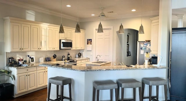 kitchen featuring appliances with stainless steel finishes, hanging light fixtures, a kitchen bar, and light stone counters