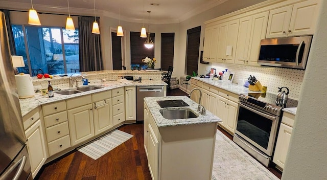 kitchen with sink, kitchen peninsula, appliances with stainless steel finishes, and decorative light fixtures