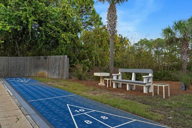 view of community featuring fence and shuffleboard