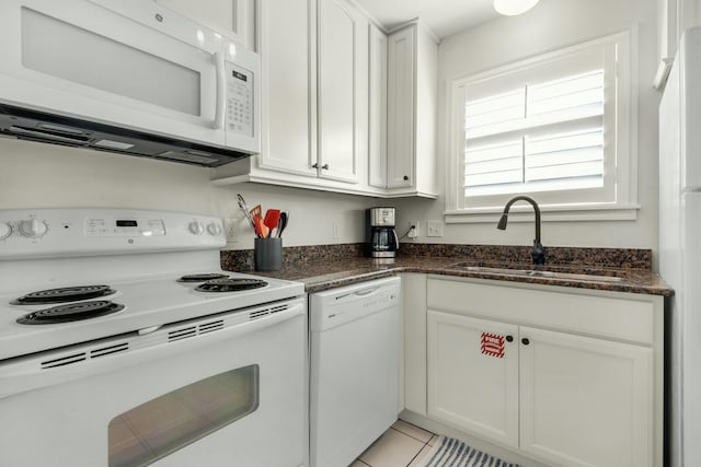 kitchen with dark stone counters, white appliances, a sink, and white cabinetry