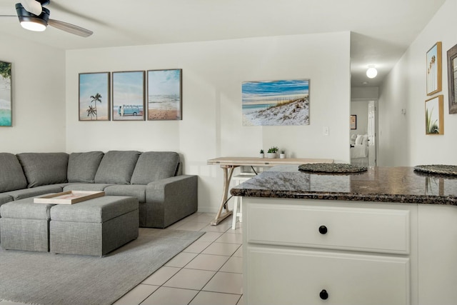 living area with light tile patterned floors and a ceiling fan