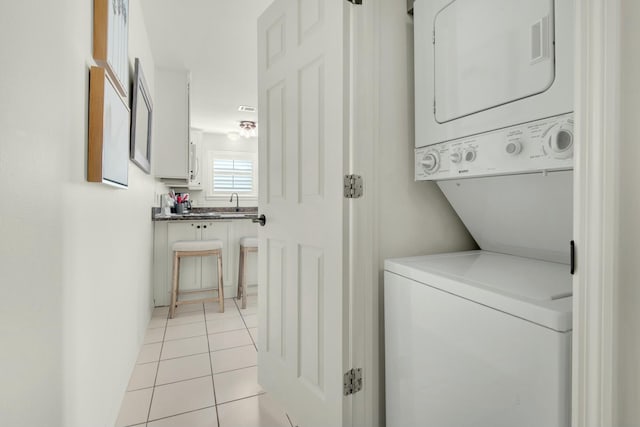 washroom featuring light tile patterned floors, laundry area, and stacked washer and clothes dryer