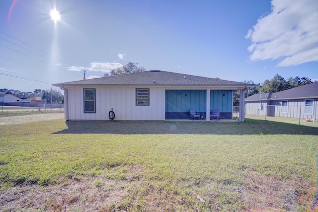 rear view of house featuring board and batten siding, a patio area, a yard, and fence