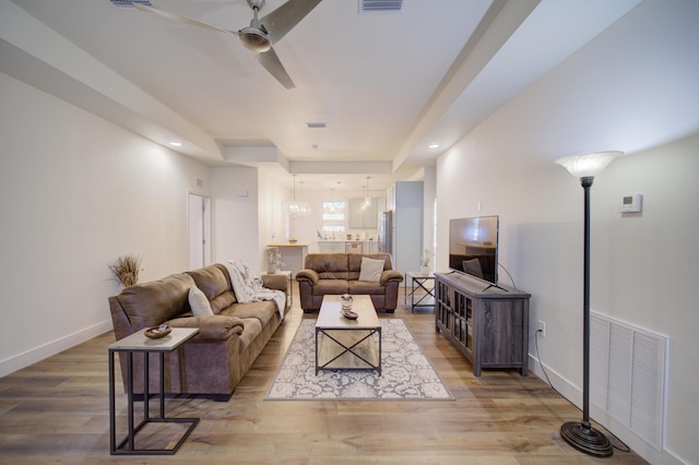 living room with baseboards, ceiling fan, visible vents, and light wood-style floors