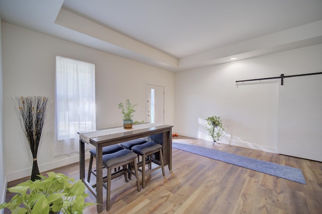 dining area featuring wood finished floors, baseboards, and a barn door