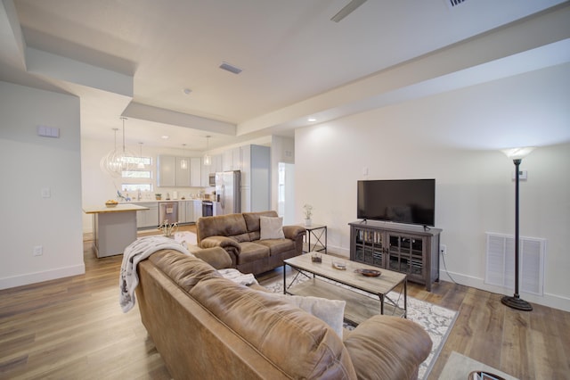 living room featuring light wood-type flooring, baseboards, and visible vents