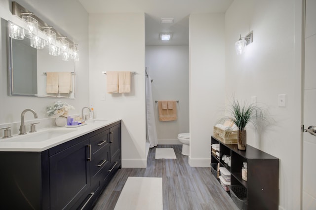 full bath with baseboards, a sink, toilet, and wood finished floors