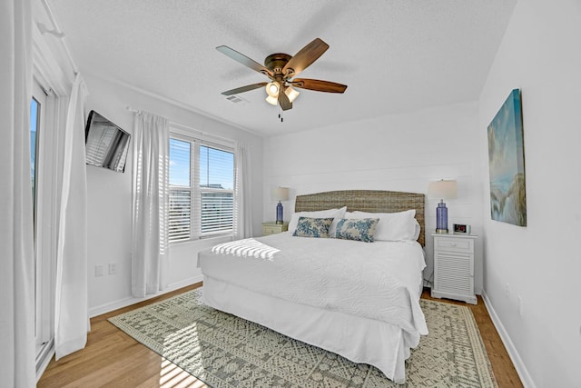 bedroom with ceiling fan, light hardwood / wood-style floors, and a textured ceiling