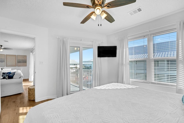 bedroom featuring a textured ceiling, access to exterior, ceiling fan, and wood-type flooring