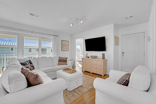 living room featuring light wood-type flooring and a textured ceiling