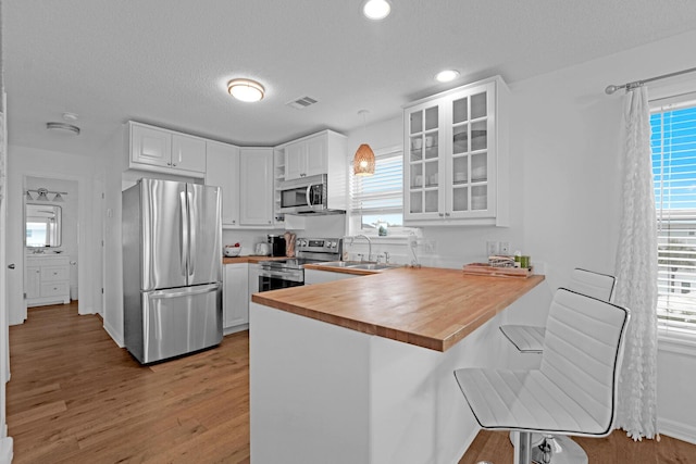 kitchen with white cabinetry, kitchen peninsula, a kitchen bar, and stainless steel appliances