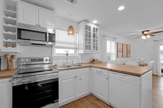 kitchen featuring appliances with stainless steel finishes, pendant lighting, sink, white cabinetry, and kitchen peninsula