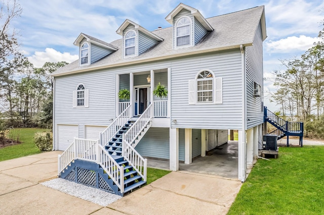 view of front facade featuring central air condition unit, a shingled roof, stairs, concrete driveway, and a front yard