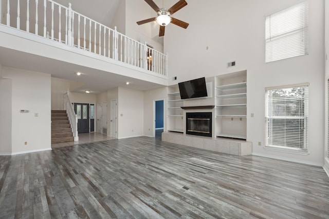 unfurnished living room featuring visible vents, stairway, wood finished floors, and a tile fireplace