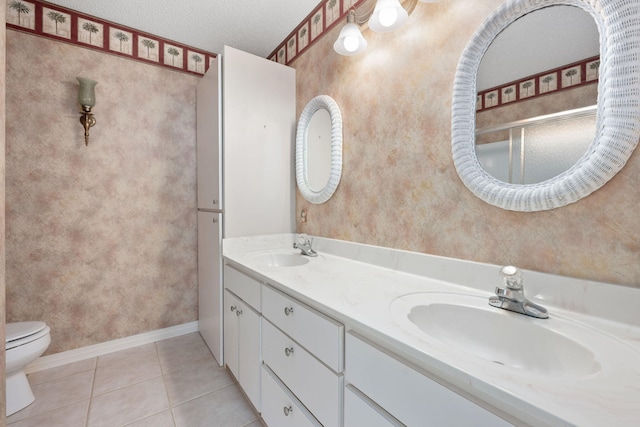 full bathroom with double vanity, a sink, toilet, and tile patterned floors