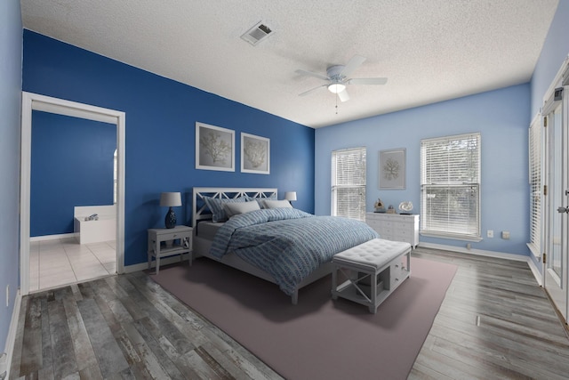 bedroom with a textured ceiling, wood finished floors, visible vents, and baseboards