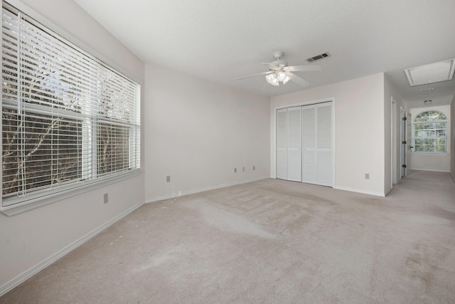 unfurnished bedroom with carpet floors, a closet, visible vents, attic access, and baseboards