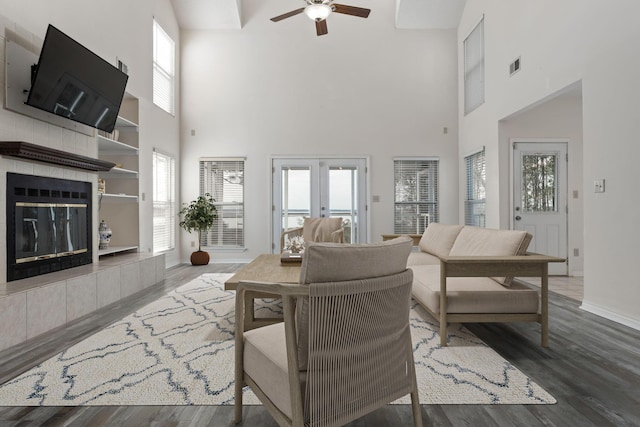 living room with french doors, visible vents, wood finished floors, a tile fireplace, and baseboards