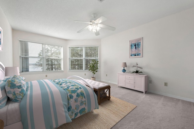 bedroom with light carpet, ceiling fan, baseboards, and a textured ceiling