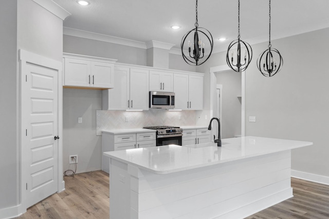 1720 25th St, Niceville, FL 32578 - kitchen with appliances with stainless steel finishes, a chandelier, light wood finished floors, backsplash, and white cabinets