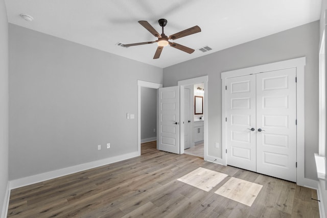 1720 25th St, Niceville, FL 32578 - unfurnished bedroom featuring a closet, wood finished floors, baseboards, ensuite bathroom, and a ceiling fan