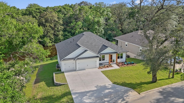 1720 25th St, Niceville, FL 32578 - view of front facade featuring concrete driveway, a garage, roof with shingles, a front yard, and a forest view