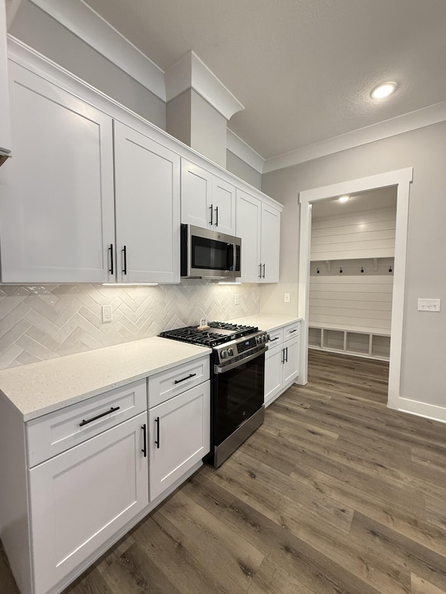 1720 25th St, Niceville, FL 32578 - kitchen featuring appliances with stainless steel finishes, white cabinets, tasteful backsplash, crown molding, and dark wood-style flooring