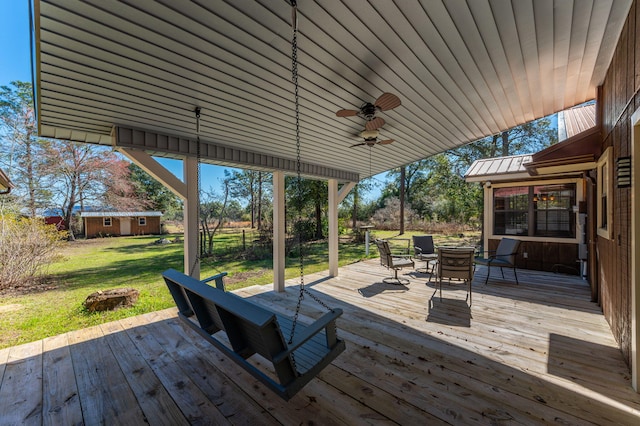 wooden terrace featuring a fire pit, a ceiling fan, and a yard